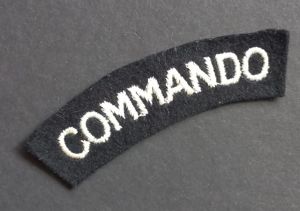 A superb - albeit regrettably single - mid war period white on black embroided commando shoulder title